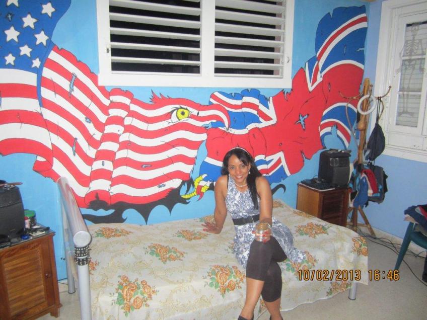Tania at her house in Havana, with a mural painted by her son.